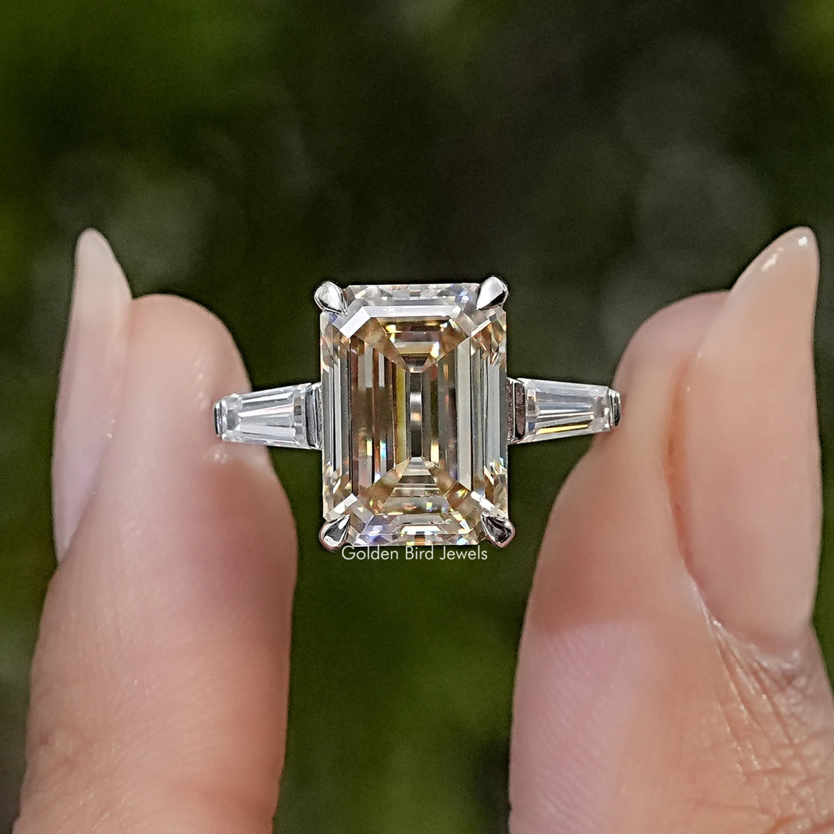 Three-stone engagement ring with a large emerald-cut center stone and tapered side stones in sterling silver