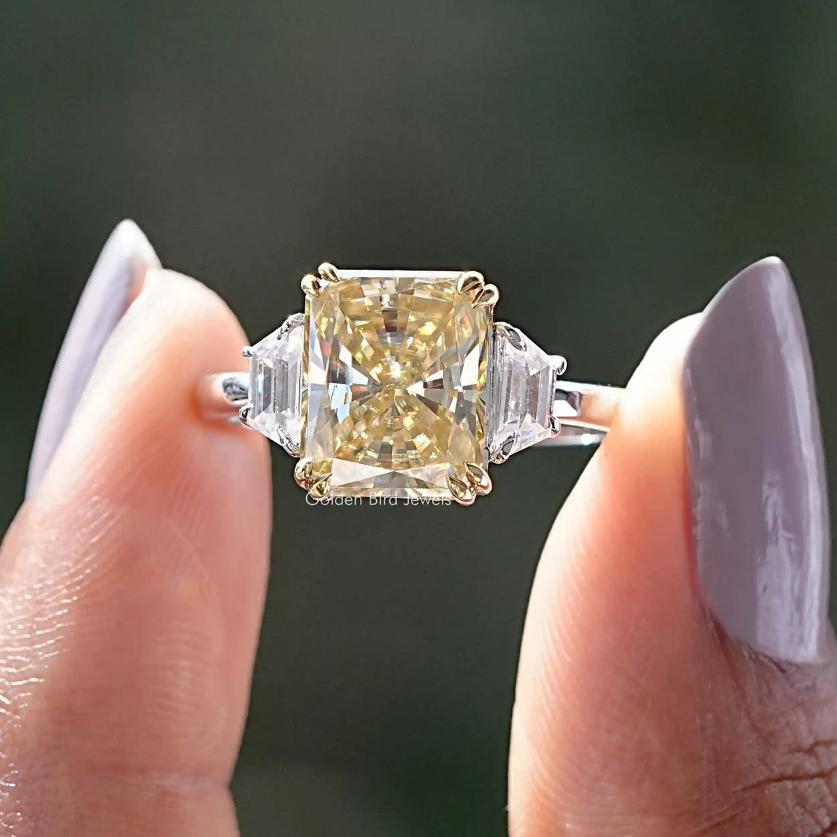 Two fingers holding the Radiant Cut 3 Stone Moissanite Engagement Ring