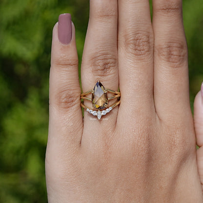 Gold-tone ring with pear-cut center stone and three-stone lower band detail