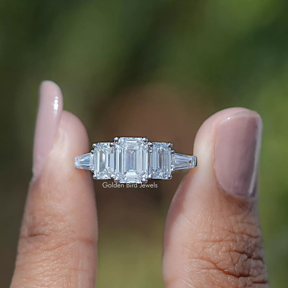 Two fingers holding the  Emerald Cut Lab Diamond Five Stone Ring