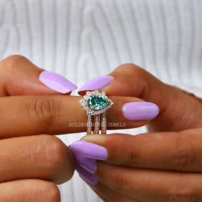 In finger front view of blue pear moissanite wedding ring 
